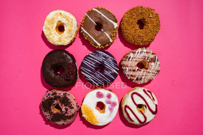 Variedad de rosquillas sobre fondo rosa - foto de stock