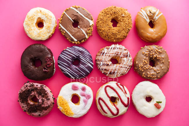 Разнообразие пончиков на розовом фоне — стоковое фото
