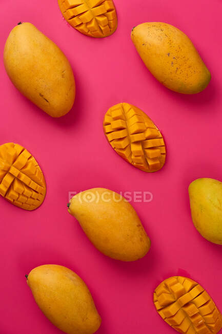 Плоские фрукты манго нарезаны пополам кубиками на розовом цветном картонном фоне — стоковое фото