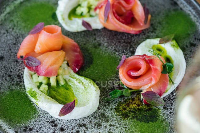 Rotoli di salmone con cipolla ed erbe aromatiche serviti su piatto rustico su tavola di legno — Foto stock