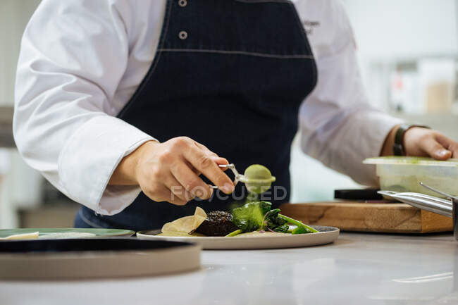 Обрізані анонімні руки людини готують смачний гастрономічний м'ясний стейк з зеленим порошком і травами, поданими на керамічній тарілці — стокове фото