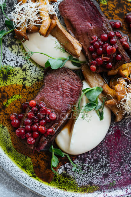 Von oben köstliches seltenes Steak mit süßer Preiselbeersoße serviert mit Kräutern und Pilzen mit Käse auf Teller — Stockfoto