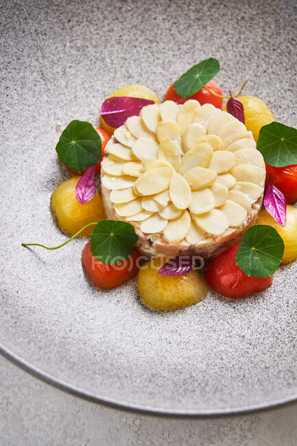 Зверху вишуканий рибний пиріг подається з мигдалем і свіжими вишневими помідорами на тарілці в ресторані — стокове фото