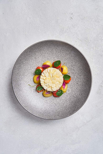 From above delectable fish tartare served with almonds and fresh cherry tomatoes on plate in restaurant — Stock Photo