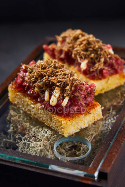 Sweet sponge cake with berry marmalade and chocolate curls placed on box with dry moss — Stock Photo