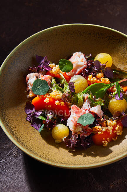 Vista superior da tigela com deliciosa salada de caranguejo com legumes frescos e ervas colocadas na mesa marrom — Fotografia de Stock