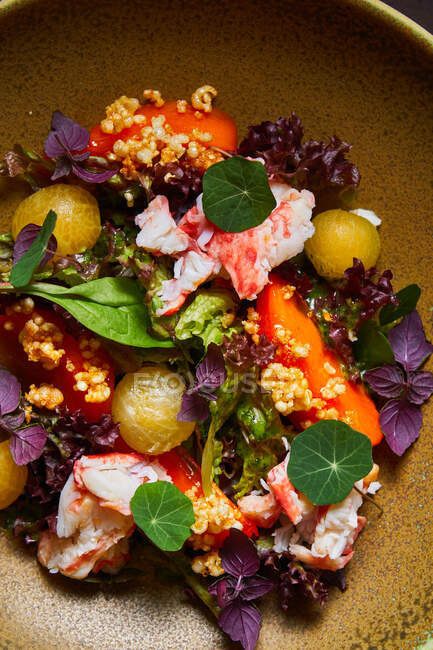 Draufsicht auf Schüssel mit köstlichem Krabbensalat mit frischem Gemüse und Kräutern auf braunem Tisch — Stockfoto