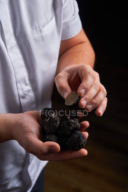 Неузнаваемый повар демонстрирует горсть черных трюфелей для приготовления изысканных блюд — стоковое фото