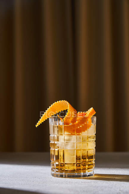 Glass cup with cold old fashioned cocktail with whiskey and orange peel placed on table in bar — Stock Photo