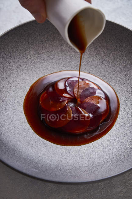 Von oben anonyme Person fügt Sauce zu köstlichen Gericht aus dünnen Scheiben gekochter Karotten und Rote Bete auf Teller — Stockfoto