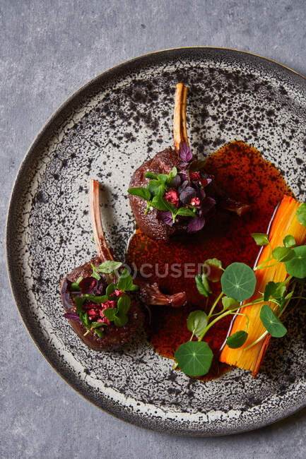 Von oben Blick auf schmackhafte Fleischmedaillons mit Kräutern auf Teller auf grauem Marmortisch — Stockfoto