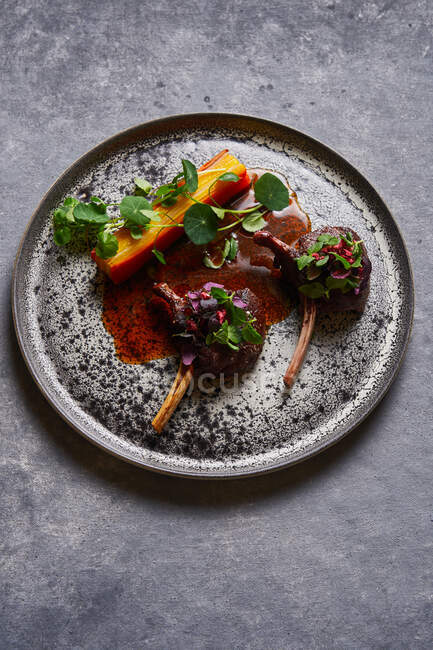 Von oben Blick auf schmackhafte Fleischmedaillons mit Kräutern auf Teller auf grauem Marmortisch — Stockfoto