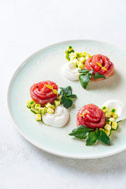 Rolos de salmão com cebola e ervas servidos em placa de cerâmica branca no fundo da mesa branca — Fotografia de Stock
