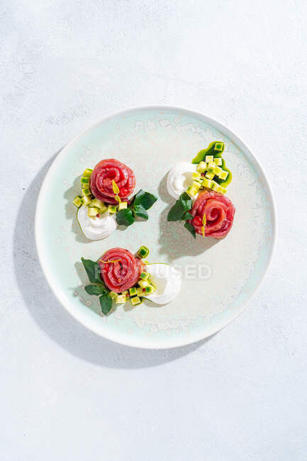 Lachsbrötchen mit Zwiebeln und Kräutern auf weißem Keramikteller auf weißem Tischhintergrund — Stockfoto