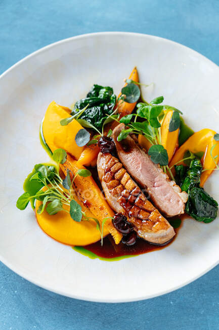 From above tasty roasted meat served with pieces of mango and pumpkin on plate in restaurant — Stock Photo