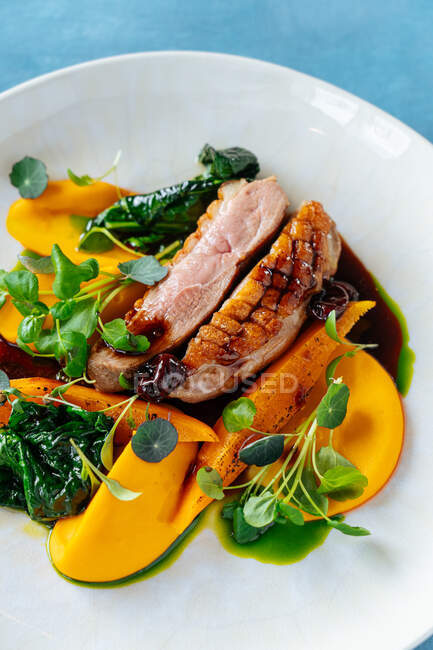 From above tasty roasted meat served with pieces of mango and pumpkin on plate in restaurant — Stock Photo