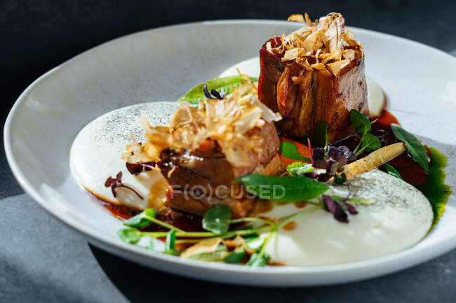 Closeup pieces of roasted meat with truffles and fresh herbs served on plate in cafe — Stock Photo