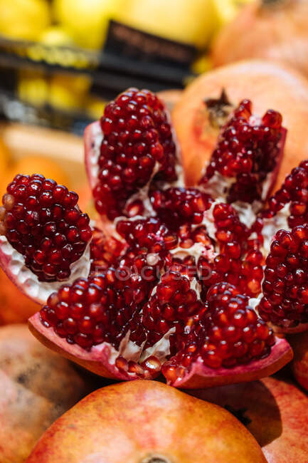 Cute fresh pomegranate placed on heap of fruits on stall in grocery store — Stock Photo