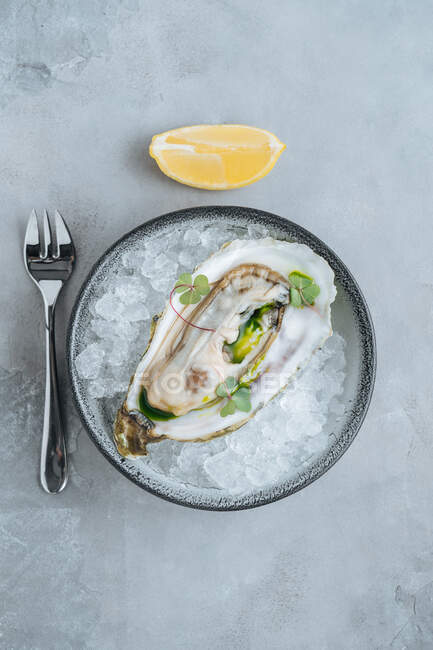 Citron sur de délicieuses huîtres sur glaçon sur un bol dans un fond blanc dans un restaurant — Photo de stock