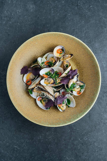 Von oben schmackhafte Miesmuscheln, serviert mit geschnittener Chilischote und frischen Basilikumblättern auf dem Teller im Restaurant — Stockfoto
