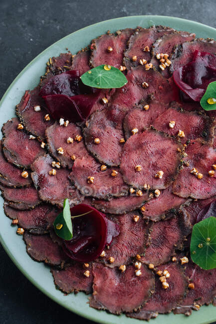Overhead savory meat carpaccio served with boiled beetroot on plate in restaurant — Stock Photo