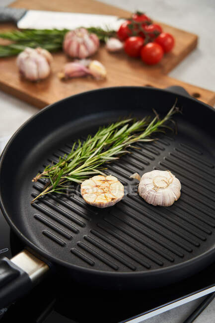 Padella alla griglia con rosmarino e aglio in cucina — Foto stock