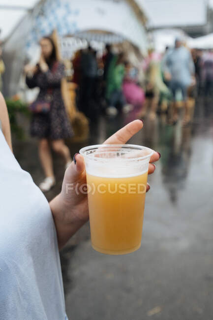 From above of crop female with plastic cup of fresh light beer in market stall on cloudy day — Stock Photo