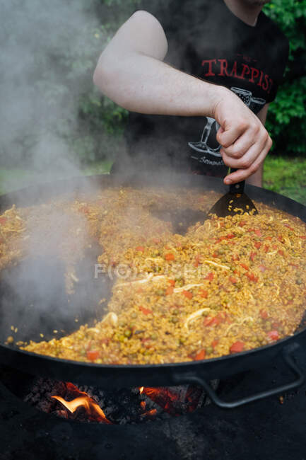 From above of crop guy in casual wear cooking traditional street paella in market stall — Stock Photo