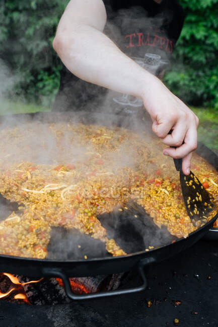 From above of crop guy in casual wear cooking traditional street paella in market stall — Stock Photo