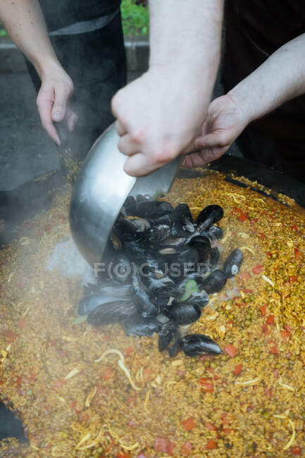 Dall'alto di ragazzi del raccolto in abbigliamento casual cucinare paella strada con cozze in bancarella mercato — Foto stock