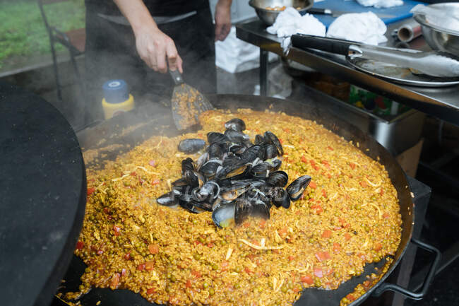 Von oben von Erntehelfern in Freizeitkleidung, die im Marktstand Straßenpaella mit Muscheln kochen — Stockfoto