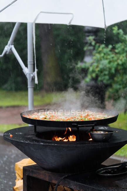 From above of cooking traditional street paella in market stall with awning on cloudy day — Stock Photo