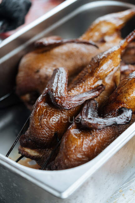 De cima de galinhas fritas cozidas em espetos metálicos na tenda de mercado — Fotografia de Stock