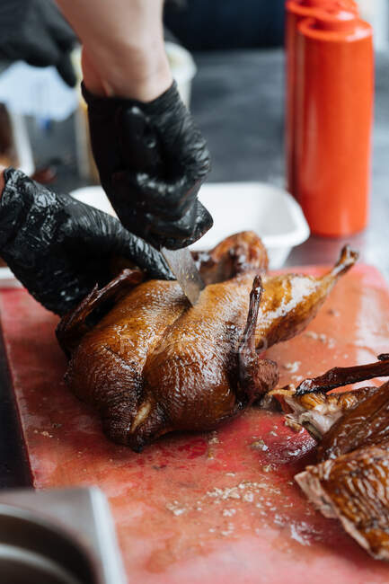 Von oben von der Ernte männlich in Handschuhen Kochen gebratenes Huhn auf Holztisch in Marktstand — Stockfoto