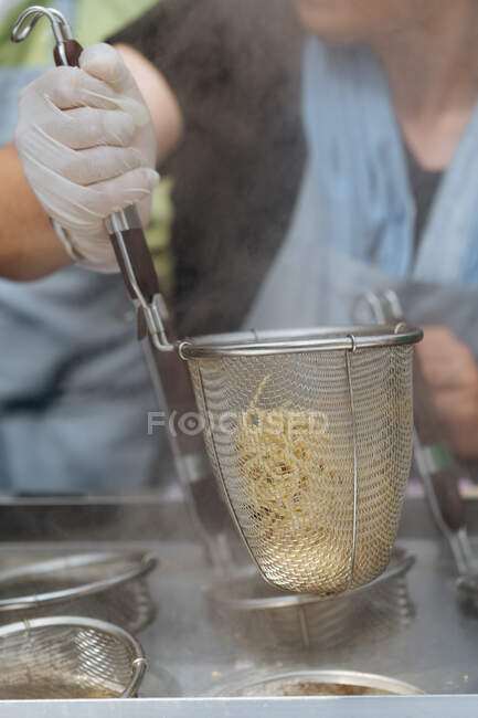 Pessoa cortada irreconhecível segurando acessório de cozinha com espaguete cozido na hora — Fotografia de Stock