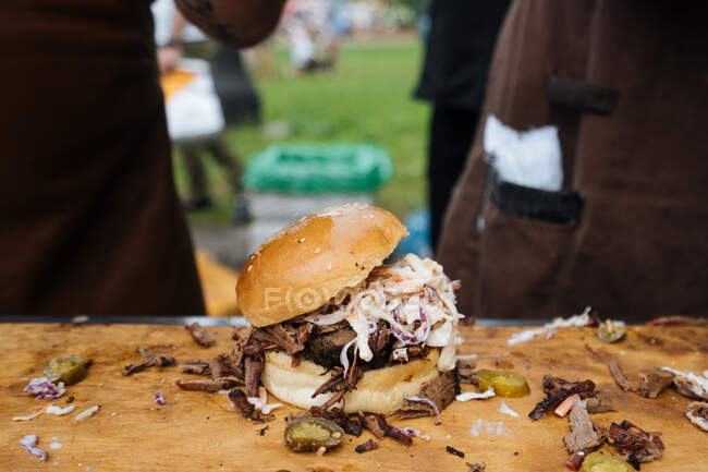 From above of burger of cucumber with cole slaw and beef in bun on table in marketplace — Stock Photo