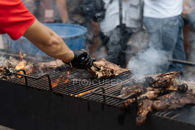 Desde arriba del chef de la cosecha convirtiendo pollo frito con humo en la parrilla en el puesto de mercado - foto de stock