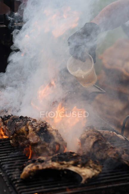 Desde arriba de cocinar pollo con humo en la parrilla en el puesto de mercado - foto de stock