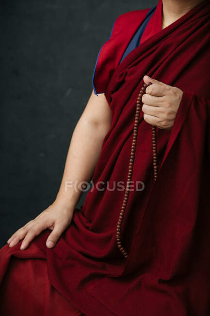 Боковий вид на буддійського монаха в традиційному червоному одязі з намистинами для молитви. — стокове фото