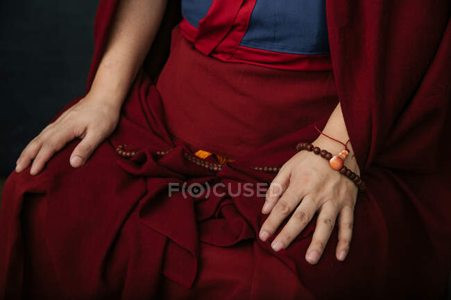 Вид сбоку на урожай буддийский монах в традиционной красной одежде с молитвенными бусами в руке — стоковое фото
