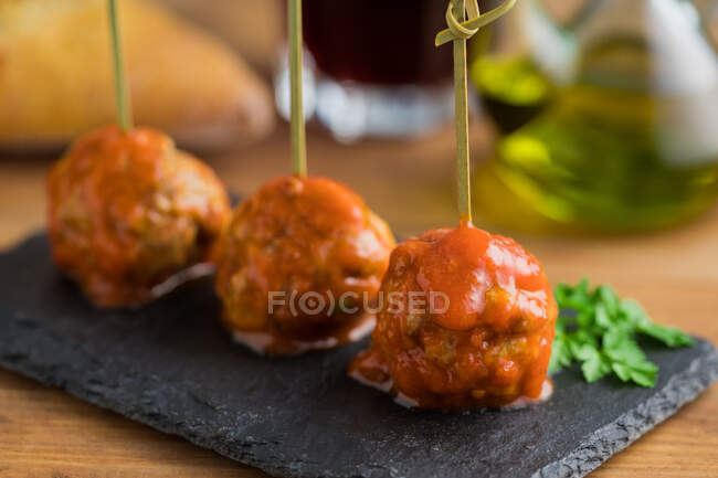 Смачні м'ясні кульки з томатним соусом, пов'язані з бамбуковими паличками на плоскій дошці на столі — стокове фото