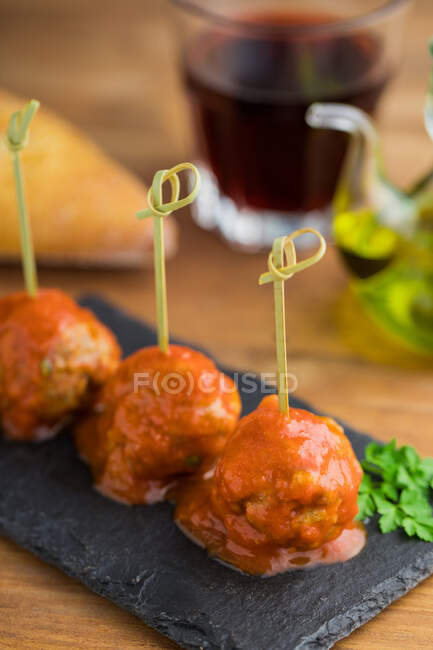 Tasty meat balls with tomato sauce bonded with bamboo sticks on flat board on table — Stock Photo