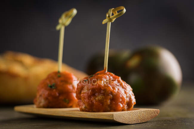 Leckere Fleischbällchen mit Tomatensauce und Bambusstäbchen auf flachem Brett auf dem Tisch — Stockfoto