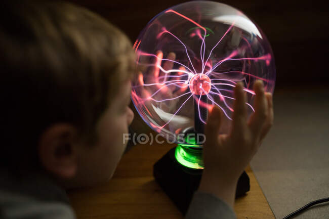 Garçon regardant mystérieuse lampe d'éclairage en verre sur la table — Photo de stock