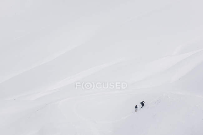 Minimalistic cold winter landscape with white snowy mountain ridge slope and climbing mountaineers — Stock Photo