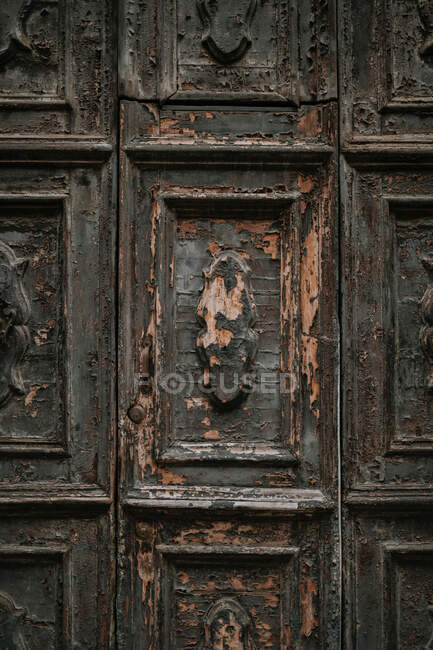 Porta vintage in legno squallido con crepe di colore e vecchi elementi decorativi tagliati — Foto stock