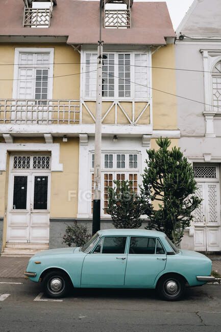 Old vintage car near white doorway on yellow building in city street — Stock Photo