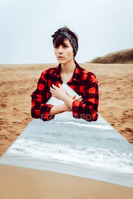 Einsame, nachdenkliche Frau mit großem Spiegel am Strand — Stockfoto