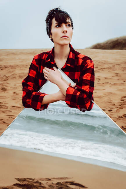 Lonely thoughtful woman with large mirror standing on beach — Stock Photo