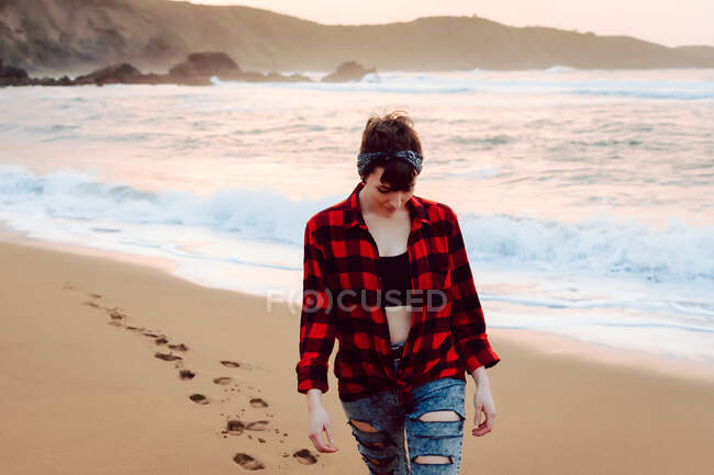 Женщина ходит по мокрому песку на пляже — стоковое фото